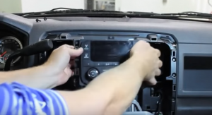 Gently lift the radio away from the dashboard and disconnect the factory wire harness from the back of the radio
