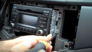 There are four screws holding the radio on the dashboard. Use a screwdriver to remove them