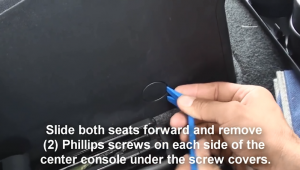 Slide both seats forwards and remove two Phillips screws on each side of the center console under the screw covers